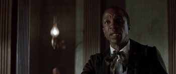 Movie still from “The League of Extraordinary Gentlemen” (2003), directed by Stephen Norrington – A man wearing a suit and tie in front of a lamp; Close Up shot, Over the shoulder angle