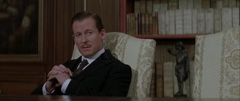 Movie still from “The League of Extraordinary Gentlemen” (2003), directed by Stephen Norrington – A man in a suit sitting in a chair in front of a bookshelf; Close Up shot, Low angle