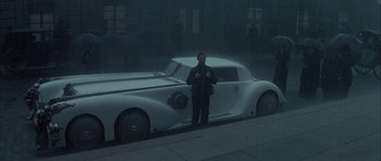 Movie still from “The League of Extraordinary Gentlemen” (2003), directed by Stephen Norrington – A man standing in front of a white car on the street; Wide shot, Low angle