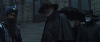 Movie still from “The League of Extraordinary Gentlemen” (2003), directed by Stephen Norrington – An older man with a hat and a black coat holding an umbrella; Medium shot, Low angle