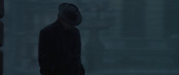 Movie still from “The League of Extraordinary Gentlemen” (2003), directed by Stephen Norrington – A person wearing a hat standing in the dark; Medium shot, Over the shoulder angle