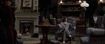 Movie still from “The League of Extraordinary Gentlemen” (2003), directed by Stephen Norrington – A man in a suit sitting in a chair in a living room; Wide shot, High angle