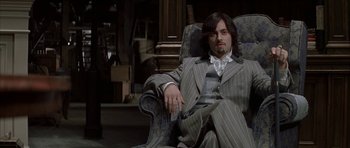 Movie still from “The League of Extraordinary Gentlemen” (2003), directed by Stephen Norrington – A man sitting in a chair holding a remote control; Medium shot, High angle