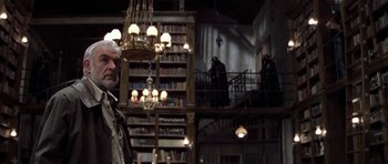 Movie still from “The League of Extraordinary Gentlemen” (2003), directed by Stephen Norrington – A man standing next to a library with a chandelier; Medium shot, Low angle