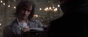 Movie still from “The League of Extraordinary Gentlemen” (2003), directed by Stephen Norrington – A man sitting at a table in front of a chandelier; Medium shot, Over the shoulder angle