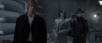Movie still from “The League of Extraordinary Gentlemen” (2003), directed by Stephen Norrington – Two men are standing in a dark room; Medium shot, Over the shoulder angle
