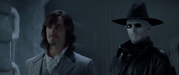 Movie still from “The League of Extraordinary Gentlemen” (2003), directed by Stephen Norrington – A man in a suit standing next to another man in a hat; Close Up shot, Over the shoulder angle