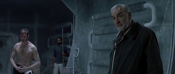 Movie still from “The League of Extraordinary Gentlemen” (2003), directed by Stephen Norrington – A man standing next to another man in a dark room; Medium shot, Low angle