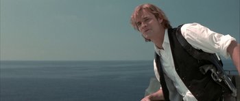 Movie still from “The League of Extraordinary Gentlemen” (2003), directed by Stephen Norrington – A man with long blonde hair sitting on top of a hill; Medium shot, Low angle