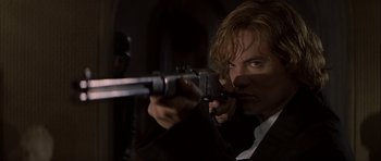 Movie still from “The League of Extraordinary Gentlemen” (2003), directed by Stephen Norrington – A man holding a gun while wearing a suit and tie; Close Up shot, Low angle