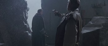 Movie still from “The League of Extraordinary Gentlemen” (2003), directed by Stephen Norrington – Two men are holding guns in a dark room; Medium shot, Over the shoulder angle