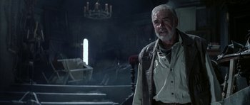 Movie still from “The League of Extraordinary Gentlemen” (2003), directed by Stephen Norrington – An older man standing next to a chair in a room; Medium shot, Low angle