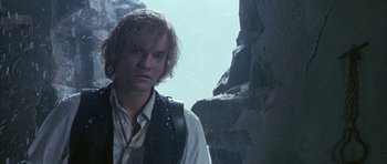 Movie still from “The League of Extraordinary Gentlemen” (2003), directed by Stephen Norrington – A man in a vest standing in front of a rock wall; Close Up shot, Low angle
