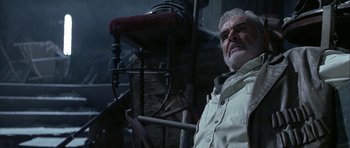 Movie still from “The League of Extraordinary Gentlemen” (2003), directed by Stephen Norrington – An older man sitting in front of an old chair; Medium shot, Low angle