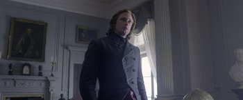 Movie still from “The Legend of Tarzan” (2016), directed by David Yates – A man in a suit standing in front of a window; Medium shot, Low angle