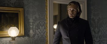 Movie still from “The Legend of Tarzan” (2016), directed by David Yates – A man standing in front of a mirror in front of a wall; Medium shot, Over the shoulder angle