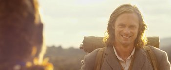 Movie still from “The Legend of Tarzan” (2016), directed by David Yates – A man with long hair is smiling for the camera; Close Up shot, Low angle