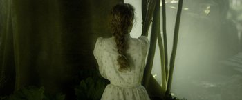 Movie still from “The Legend of Tarzan” (2016), directed by David Yates – A woman in a white dress is looking out a window; Medium shot, Over the shoulder angle