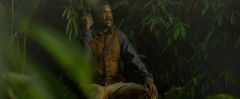 Movie still from “The Legend of Tarzan” (2016), directed by David Yates – A man sitting on the ground in the woods; Medium shot, Low angle