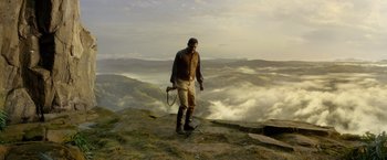 Movie still from “The Legend of Tarzan” (2016), directed by David Yates – A man standing on top of a mountain holding a rope; Wide shot, Low angle