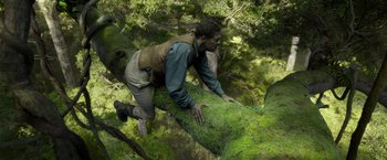 Movie still from “The Legend of Tarzan” (2016), directed by David Yates – A man climbing a tree in the woods; Wide shot, Low angle