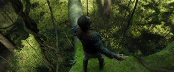 Movie still from “The Legend of Tarzan” (2016), directed by David Yates – A man standing on top of a lush green hillside; Wide shot, Overhead angle