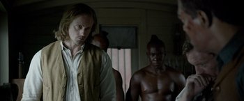 Movie still from “The Legend of Tarzan” (2016), directed by David Yates – A man standing next to another man in front of a door; Medium shot, Over the shoulder angle