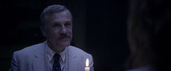 Movie still from “The Legend of Tarzan” (2016), directed by David Yates – An older man in a suit and tie holding a lit candle; Close Up shot, Over the shoulder angle