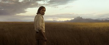 Movie still from “The Legend of Tarzan” (2016), directed by David Yates – A man standing in the middle of an open field; Medium shot, Low angle