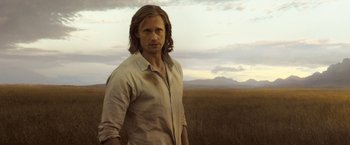 Movie still from “The Legend of Tarzan” (2016), directed by David Yates – A man standing in the middle of an open field; Medium shot, Over the shoulder angle