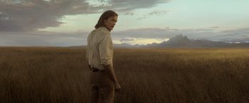 Movie still from “The Legend of Tarzan” (2016), directed by David Yates – A man standing in the middle of an open field; Medium shot, Over the shoulder angle