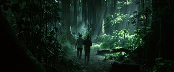 Movie still from “The Legend of Tarzan” (2016), directed by David Yates – Two people are walking through a lush green forest; Wide shot, Low angle