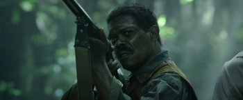 Movie still from “The Legend of Tarzan” (2016), directed by David Yates – A man holding a gun while talking on the phone; Close Up shot, Low angle