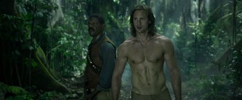 Movie still from “The Legend of Tarzan” (2016), directed by David Yates – Two men standing next to each other in the woods; Medium shot, Over the shoulder angle
