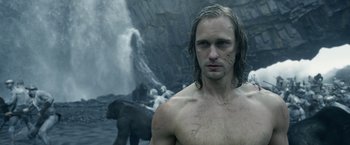 Movie still from “The Legend of Tarzan” (2016), directed by David Yates – A man with wet hair standing in front of a waterfall; Close Up shot, Low angle
