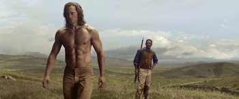 Movie still from “The Legend of Tarzan” (2016), directed by David Yates – Two men are standing in a field holding guns; Medium shot, Over the shoulder angle