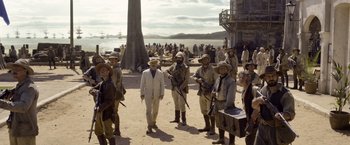 Movie still from “The Legend of Tarzan” (2016), directed by David Yates – A group of people standing on a beach with guns; Wide shot, Over the shoulder angle