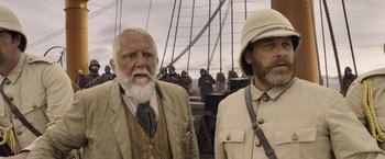 Movie still from “The Legend of Tarzan” (2016), directed by David Yates – Two men standing next to each other on a bridge; Medium shot, Low angle