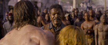Movie still from “The Legend of Tarzan” (2016), directed by David Yates – A man standing in front of a group of people; Close Up shot, Over the shoulder angle
