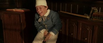 Movie still from “The Legend of Zorro” (2005), directed by Martin Campbell – A boy in a uniform laughing while sitting on a chair; Medium shot, High angle