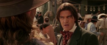 Movie still from “The Legend of Zorro” (2005), directed by Martin Campbell – A man with long hair wearing a red bow tie; Close Up shot, Over the shoulder angle