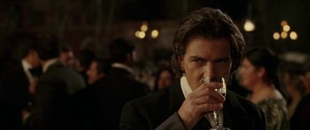 Movie still from “The Legend of Zorro” (2005), directed by Martin Campbell – A man in a tuxedo drinking a glass of wine; Close Up shot, Over the shoulder angle