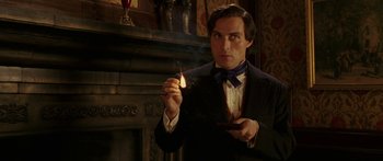 Movie still from “The Legend of Zorro” (2005), directed by Martin Campbell – A man in a suit and tie holding a burning match; Close Up shot, Low angle