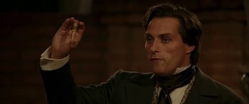 Movie still from “The Legend of Zorro” (2005), directed by Martin Campbell – A man in a suit holding a small bottle; Close Up shot, Low angle