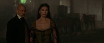 Movie still from “The Legend of Zorro” (2005), directed by Martin Campbell – A woman in a dress standing in a dark room; Medium shot, Over the shoulder angle