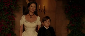 Movie still from “The Legend of Zorro” (2005), directed by Martin Campbell – A woman standing next to a young boy in front of candles; Medium shot, Low angle