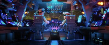 Movie still from “The Lego Batman Movie” (2017), directed by Chris McKay – Two lego figures are sitting in front of a control panel; Wide shot, Overhead angle