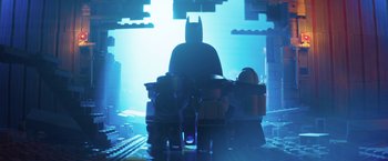 Movie still from “The Lego Batman Movie” (2017), directed by Chris McKay – A lego batman figure sitting on top of a table; Wide shot, Over the shoulder angle