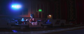 Movie still from “The Lego Batman Movie” (2017), directed by Chris McKay – A lego batman sitting on a couch in a room; Wide shot, Over the shoulder angle
