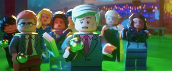 Movie still from “The Lego Batman Movie” (2017), directed by Chris McKay – A lego man that is standing in front of some people; Close Up shot, Over the shoulder angle